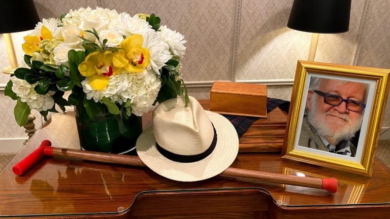 a table with a photo of a bearded man, a cane, and a vase full of flowers